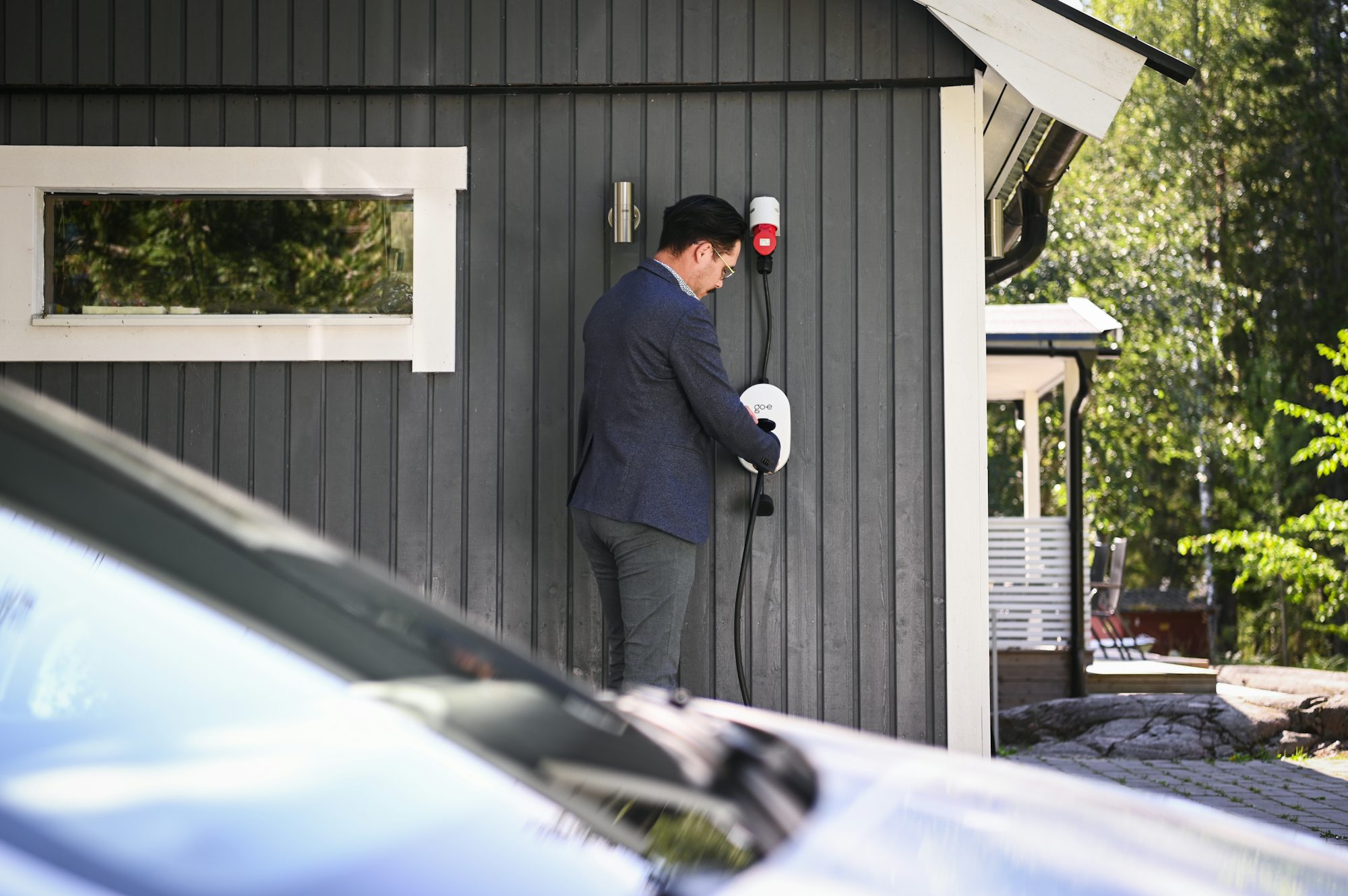 Hand plugging a charging cable into an EV's charging port