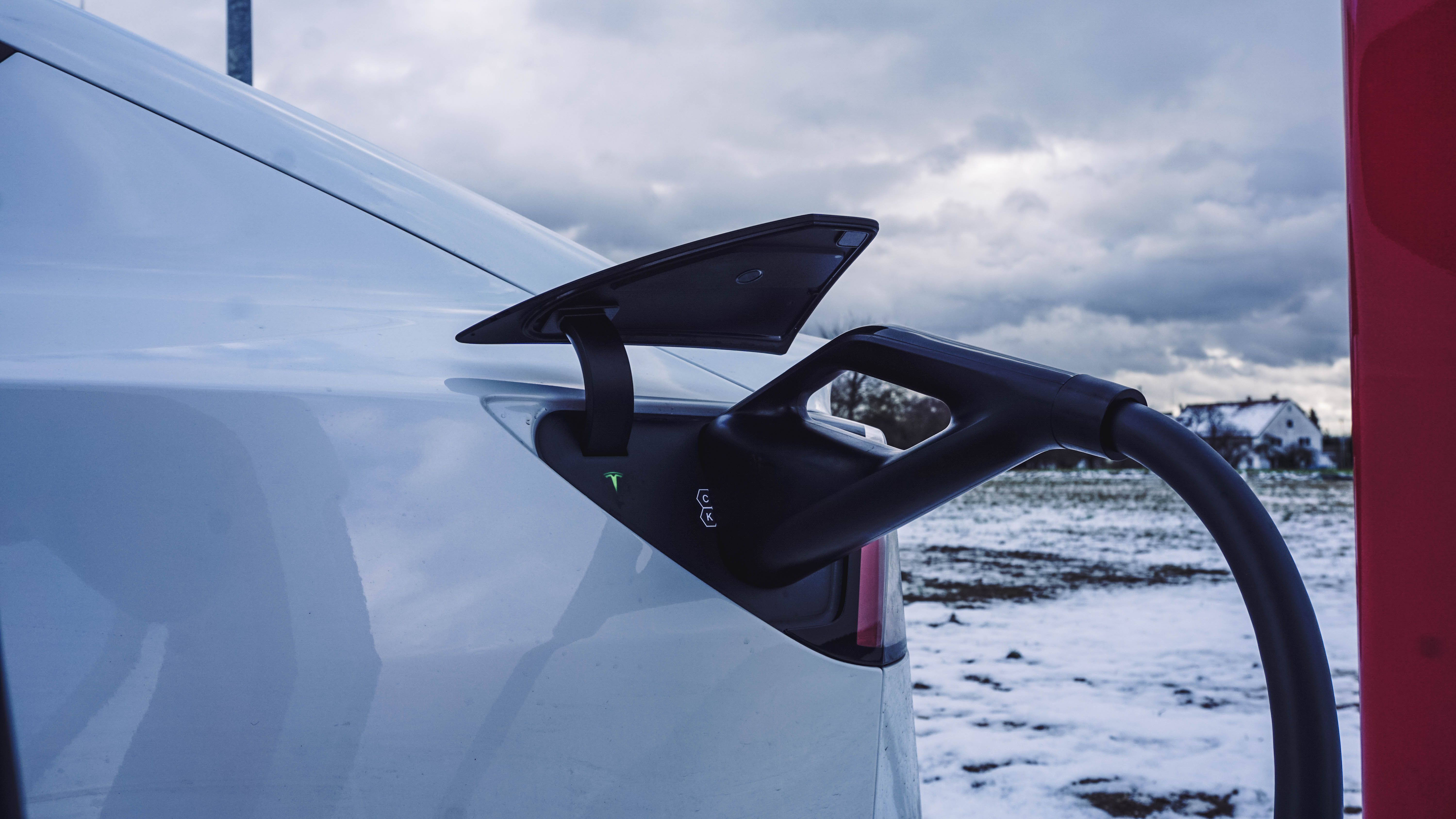 Charging connector plugged into a white electric car outdoors