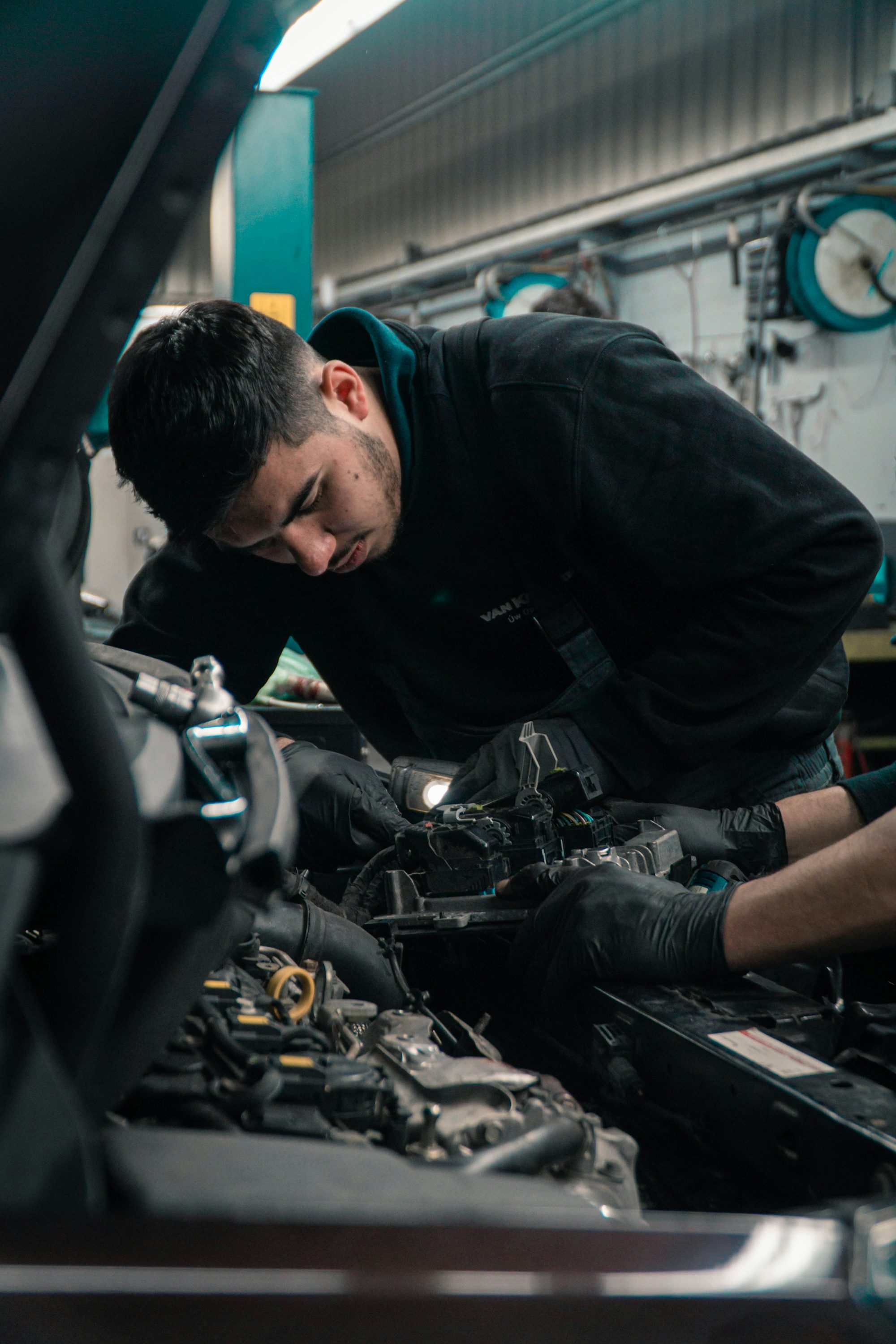 A mechanic's hands working on a car's engine and electrical components