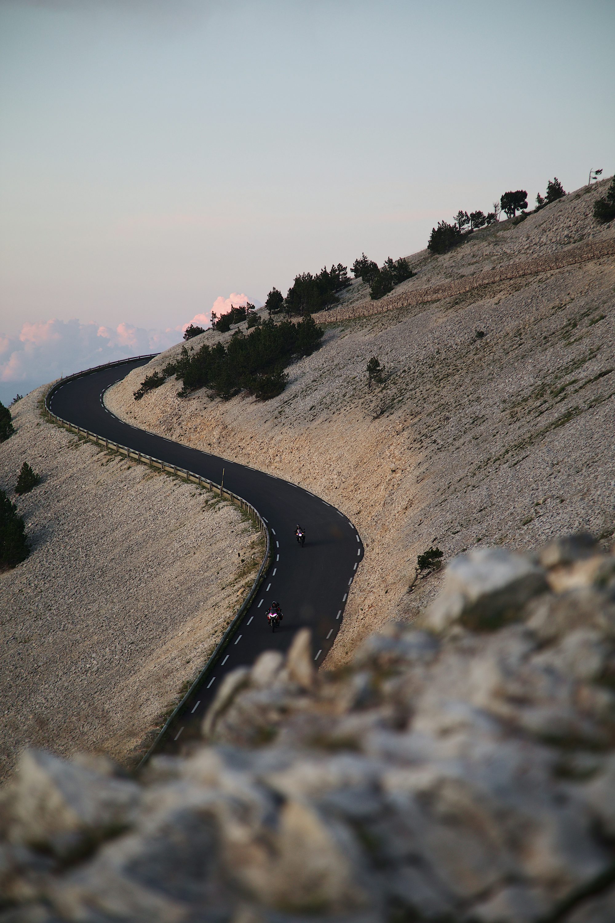 A car driving a winding mountain road at sunset