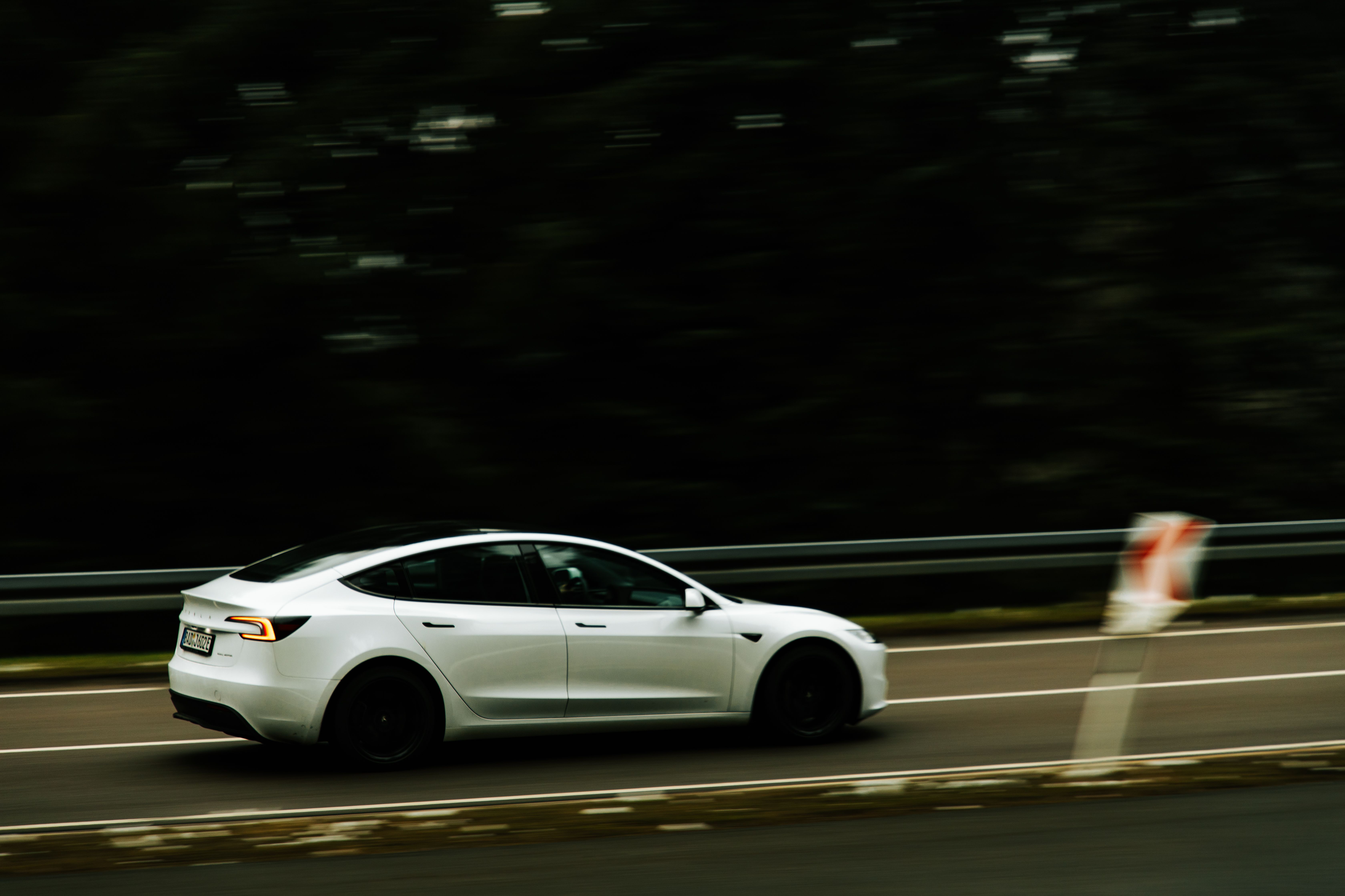 An electric car in motion on a highway, motion-blur panning shot